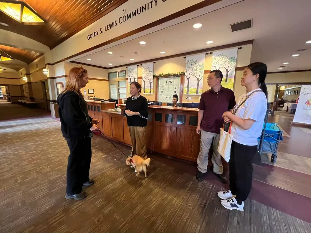 Visitors chat in the community center lobby, one with a small dog on a leash.