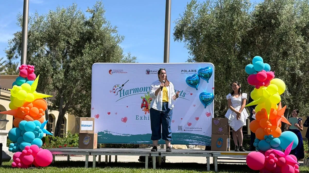 The outdoor stage with the Harmony of Hearts backdrop and balloon towers on either side.