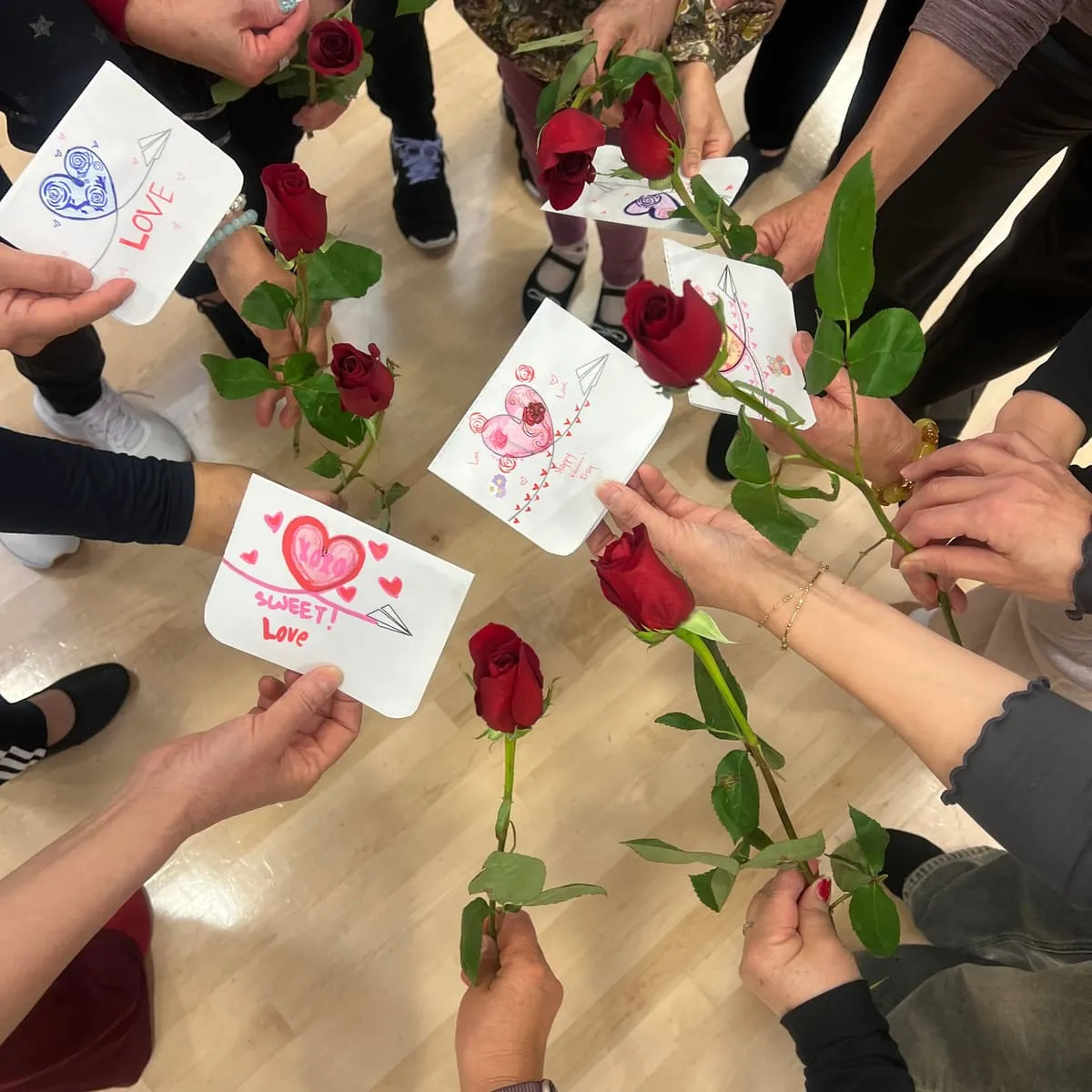 Hands hold out red roses and handmade cards.