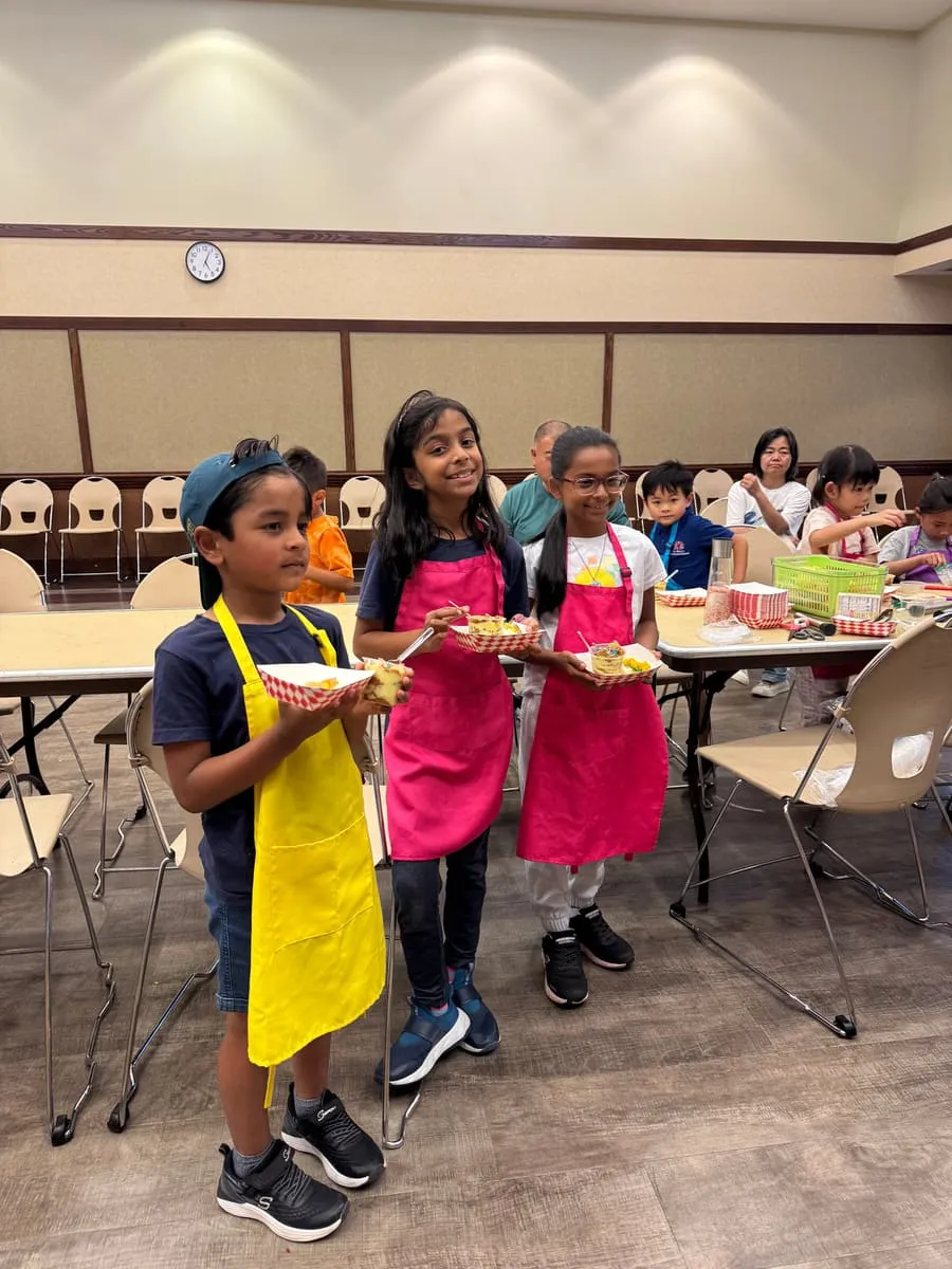 Children in aprons hold up the plates they made.