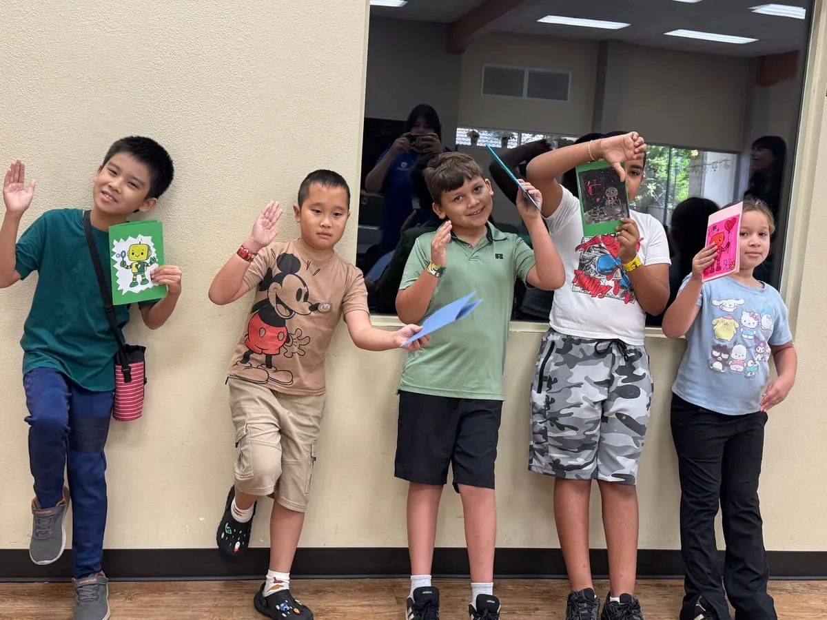 Five boys pose against a wall holding the crafts they made.