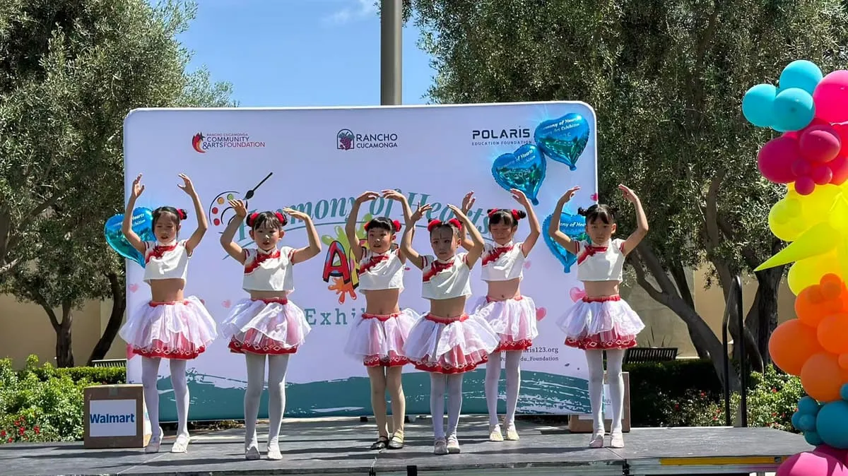 Young dancers in pink tutus perform on the outdoor stage.