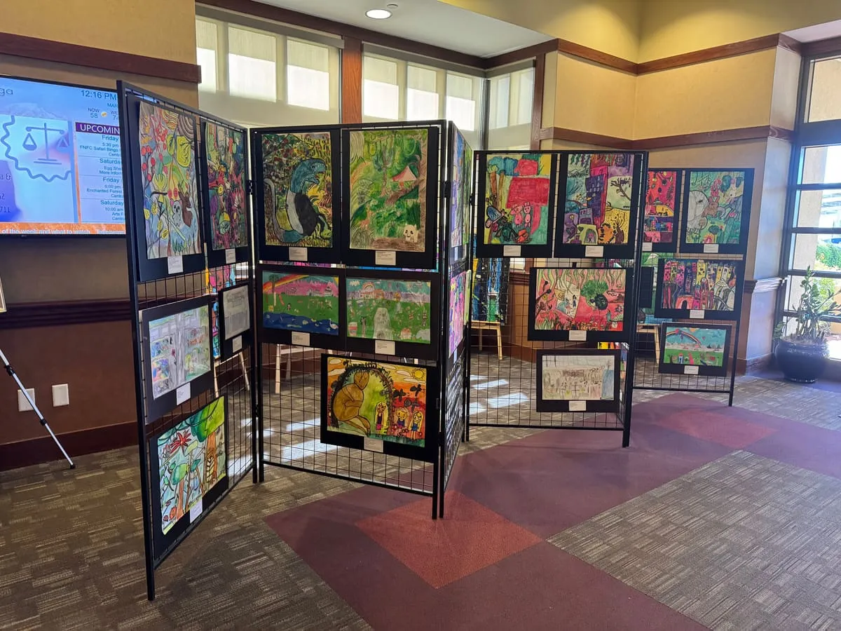 Panels of student paintings stand in a carpeted hall.
