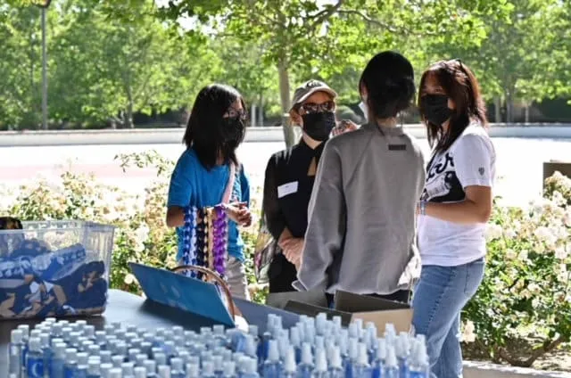 Volunteers hand out bottled water at an outdoor table.