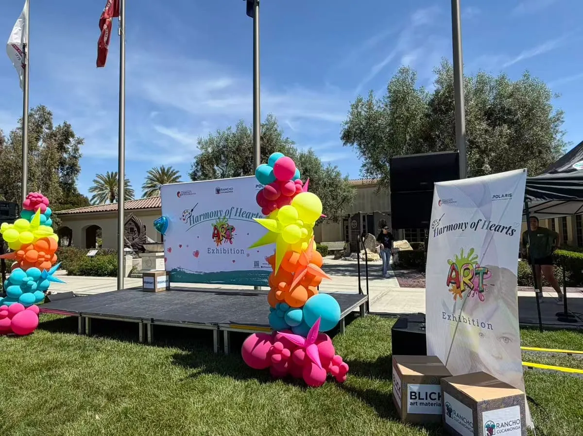 The outdoor stage set up on a lawn, with a balloon tower and the exhibition banner.