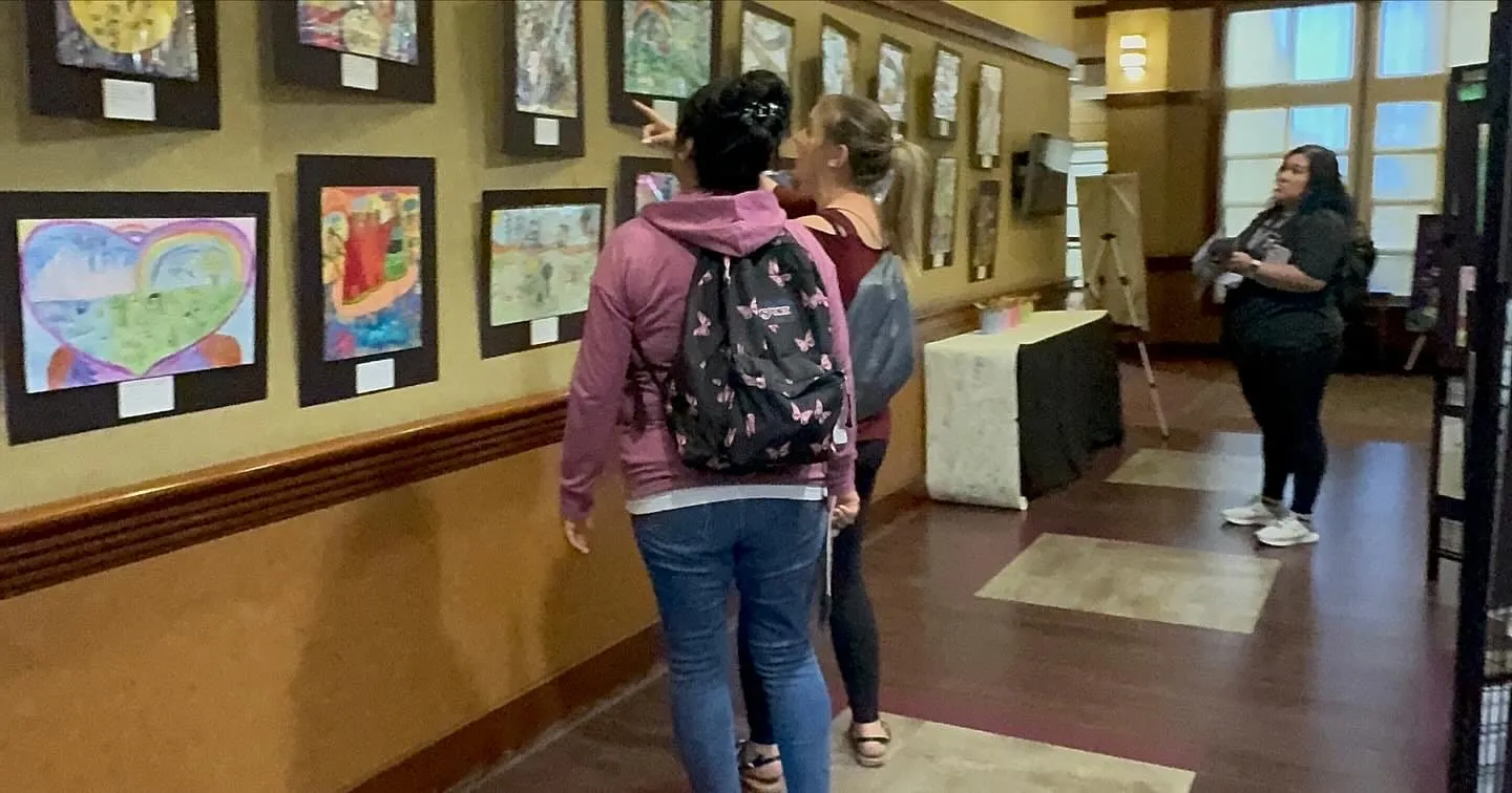 Visitors walk the corridor of framed student artwork at the Goldy S. Lewis Community Center.